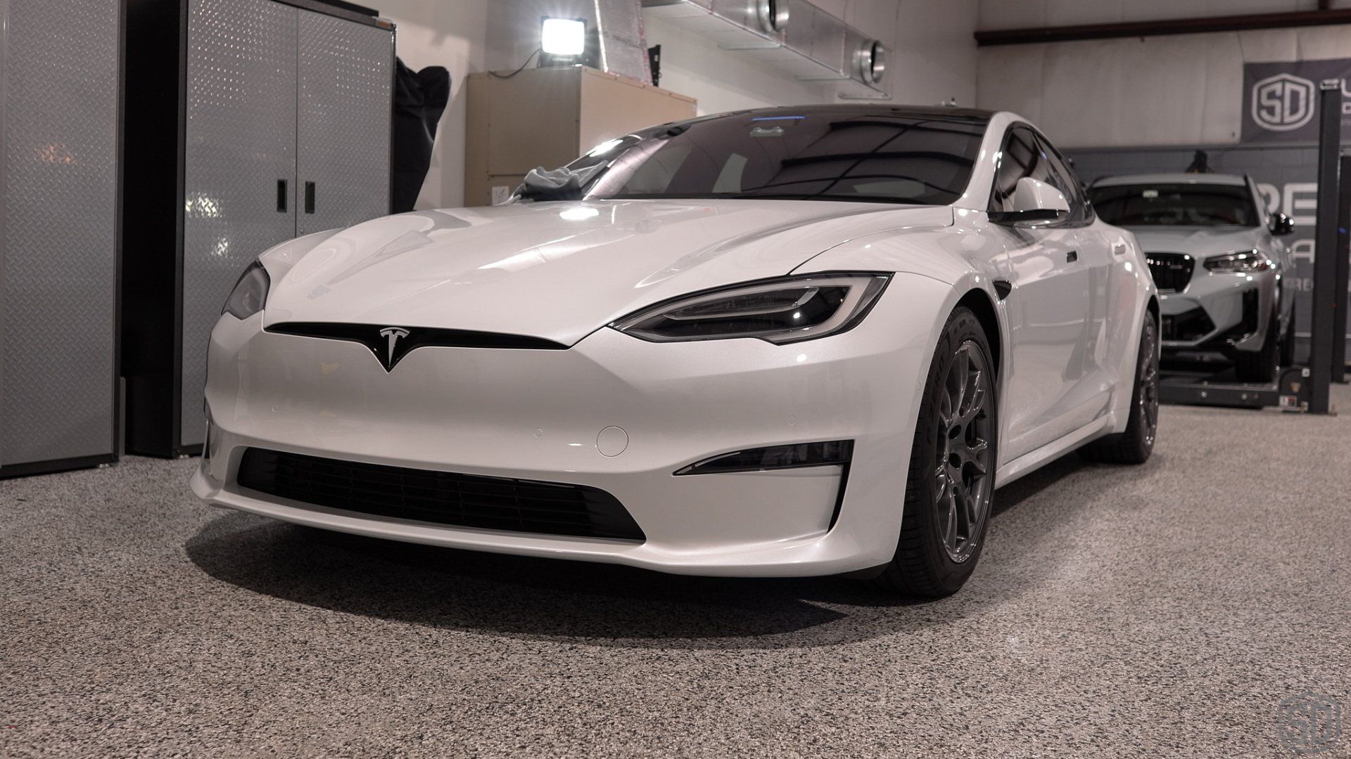 A white tesla model s is parked in a garage.