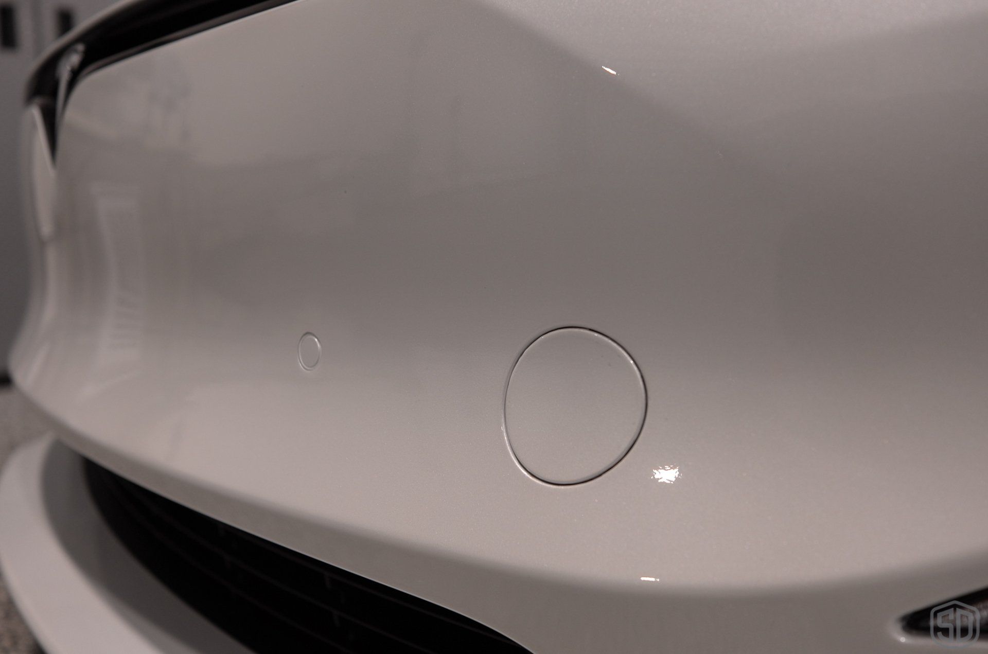 A close up of a white car 's bumper with a circle on it.