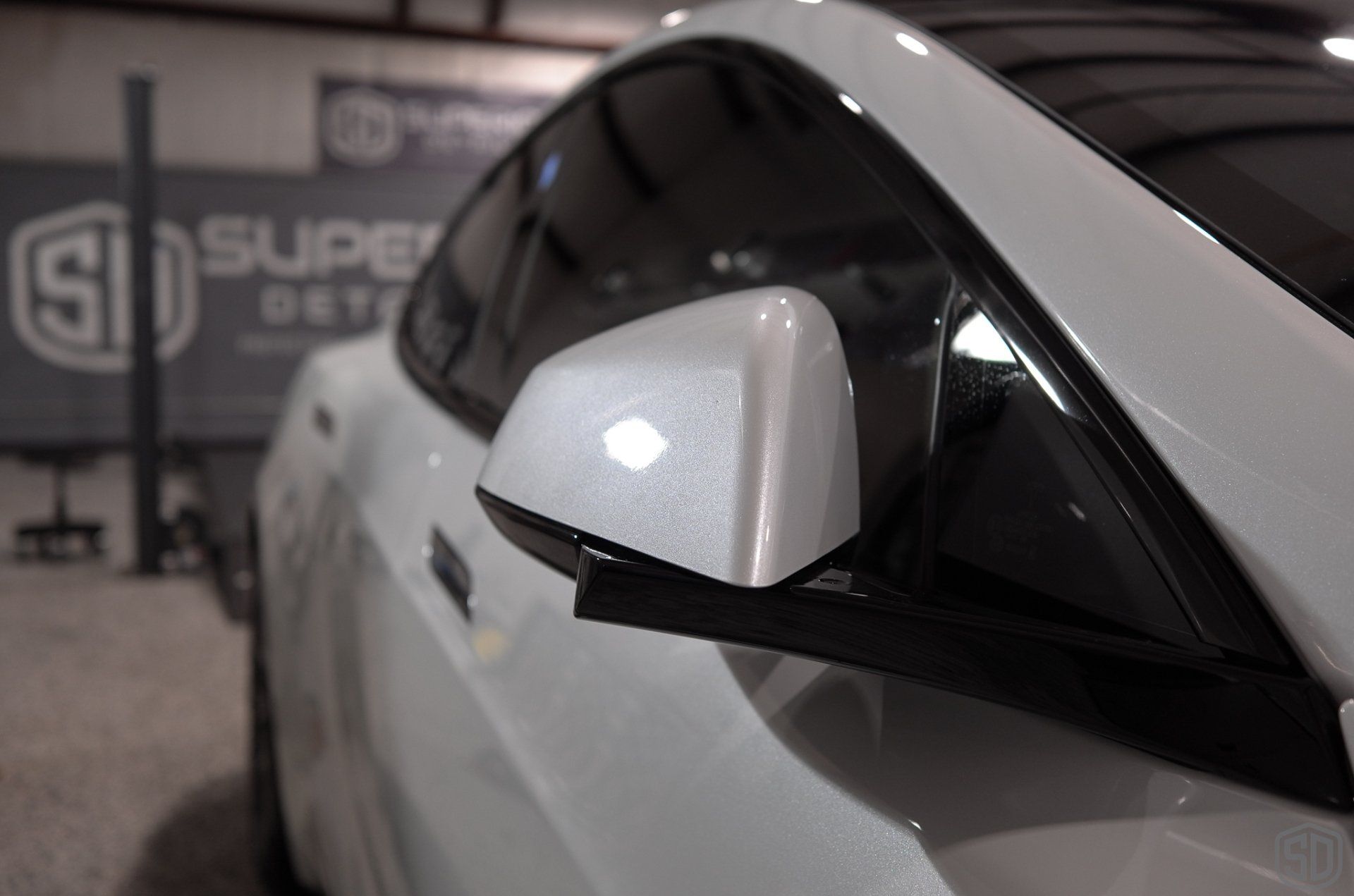 A close up of a white car 's side mirror in a garage.