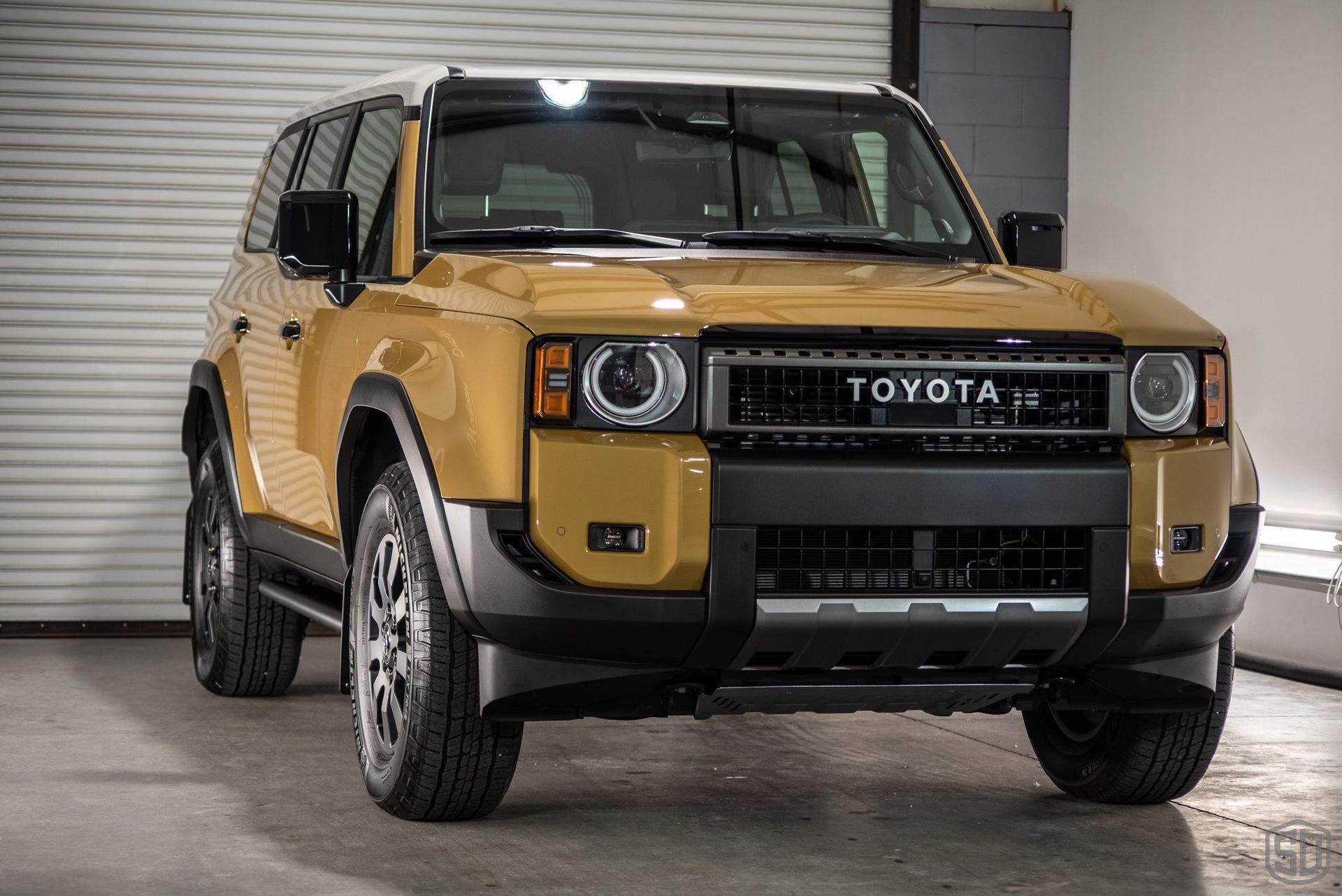 A yellow toyota suv is parked in front of a garage door.