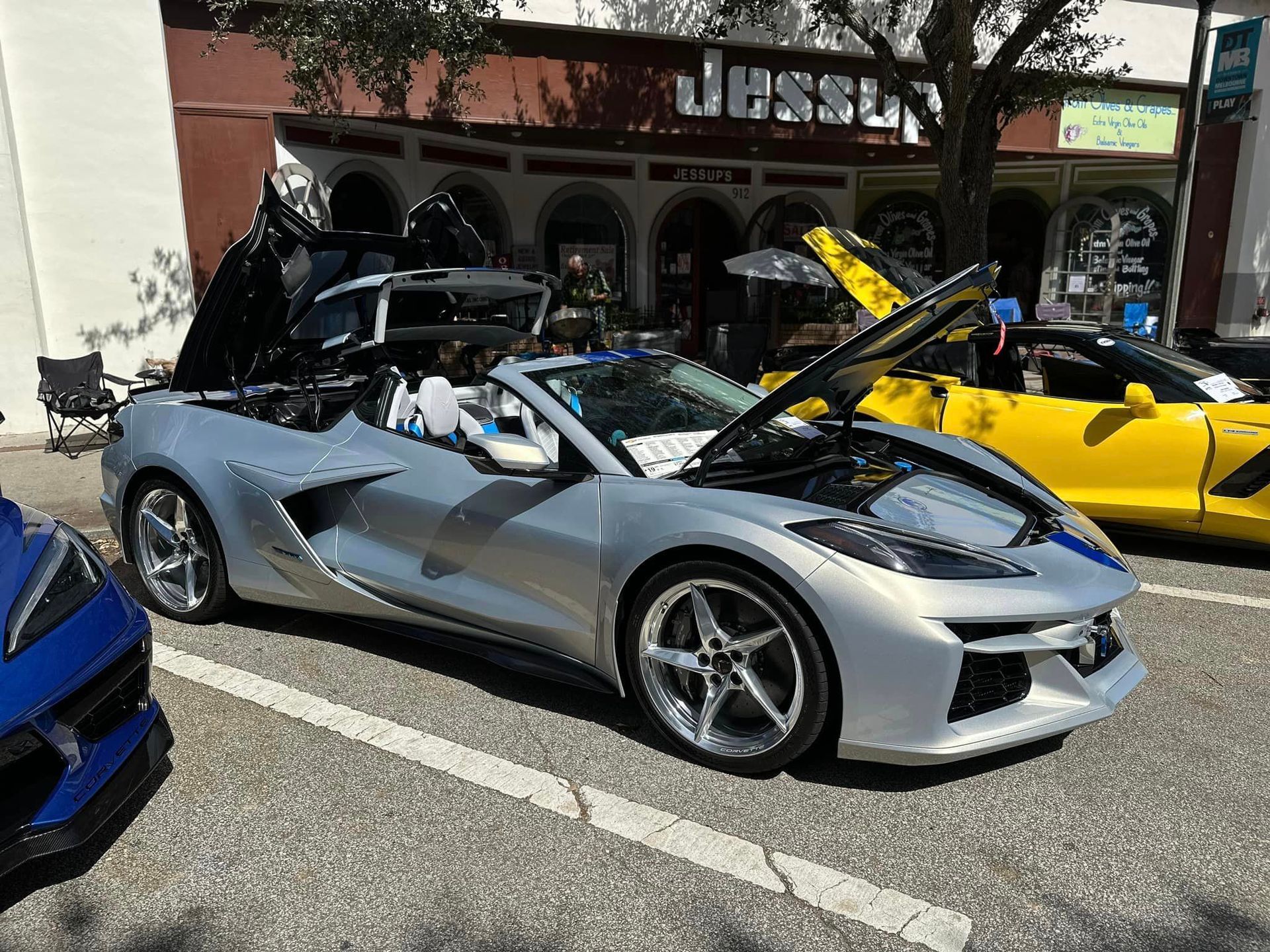 A silver sports car is parked next to a yellow sports car.