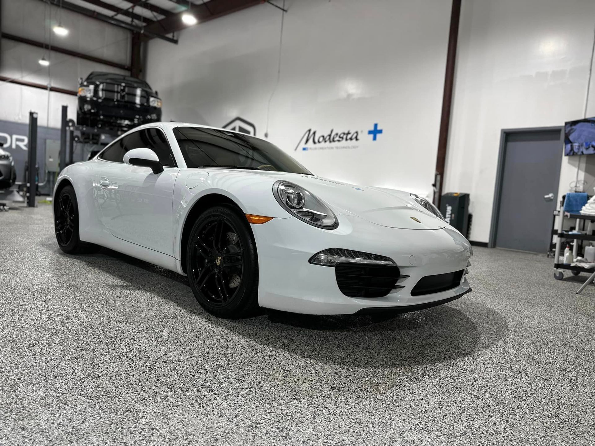 A white porsche 911 is parked in a garage.