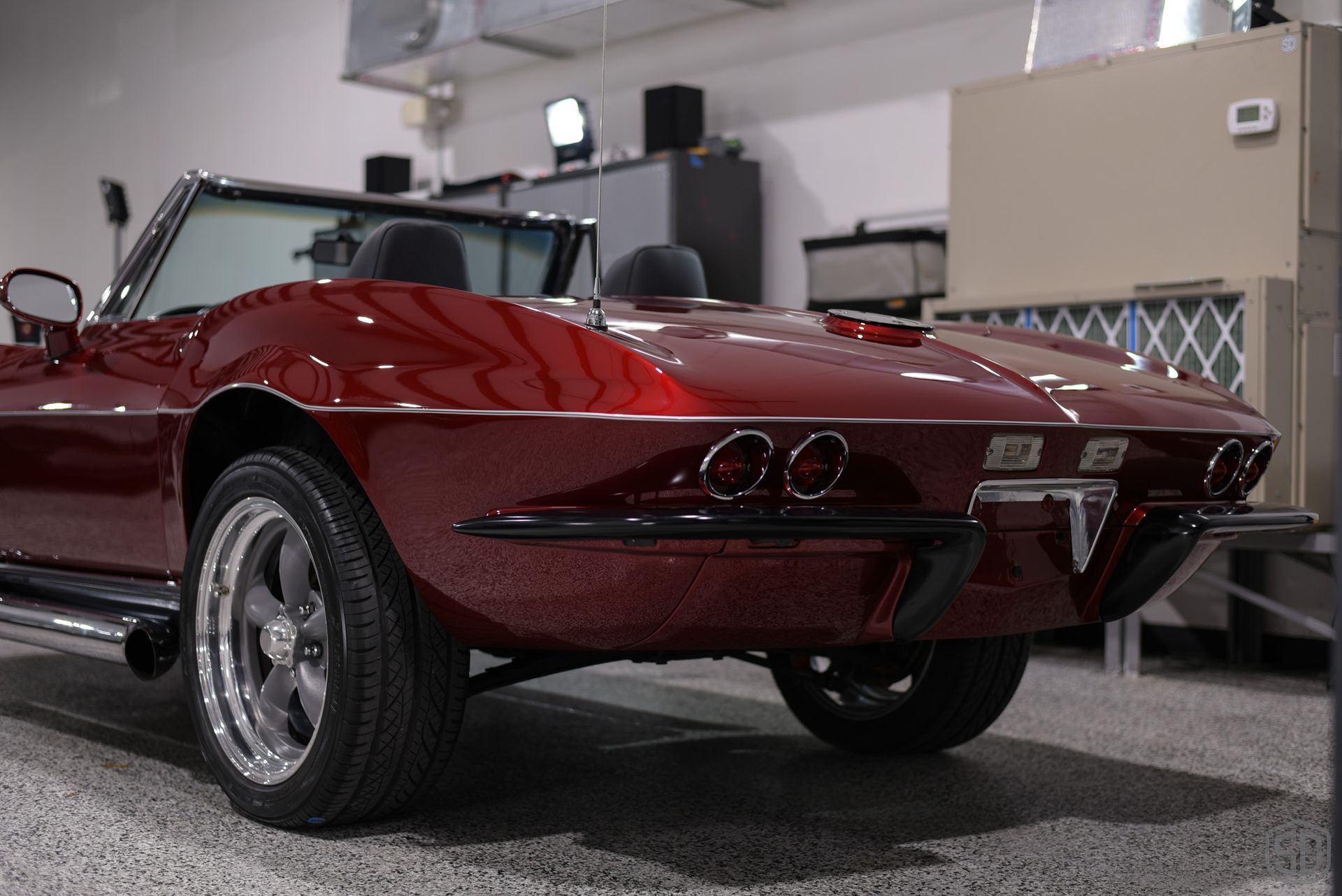 A red corvette convertible is parked in a garage