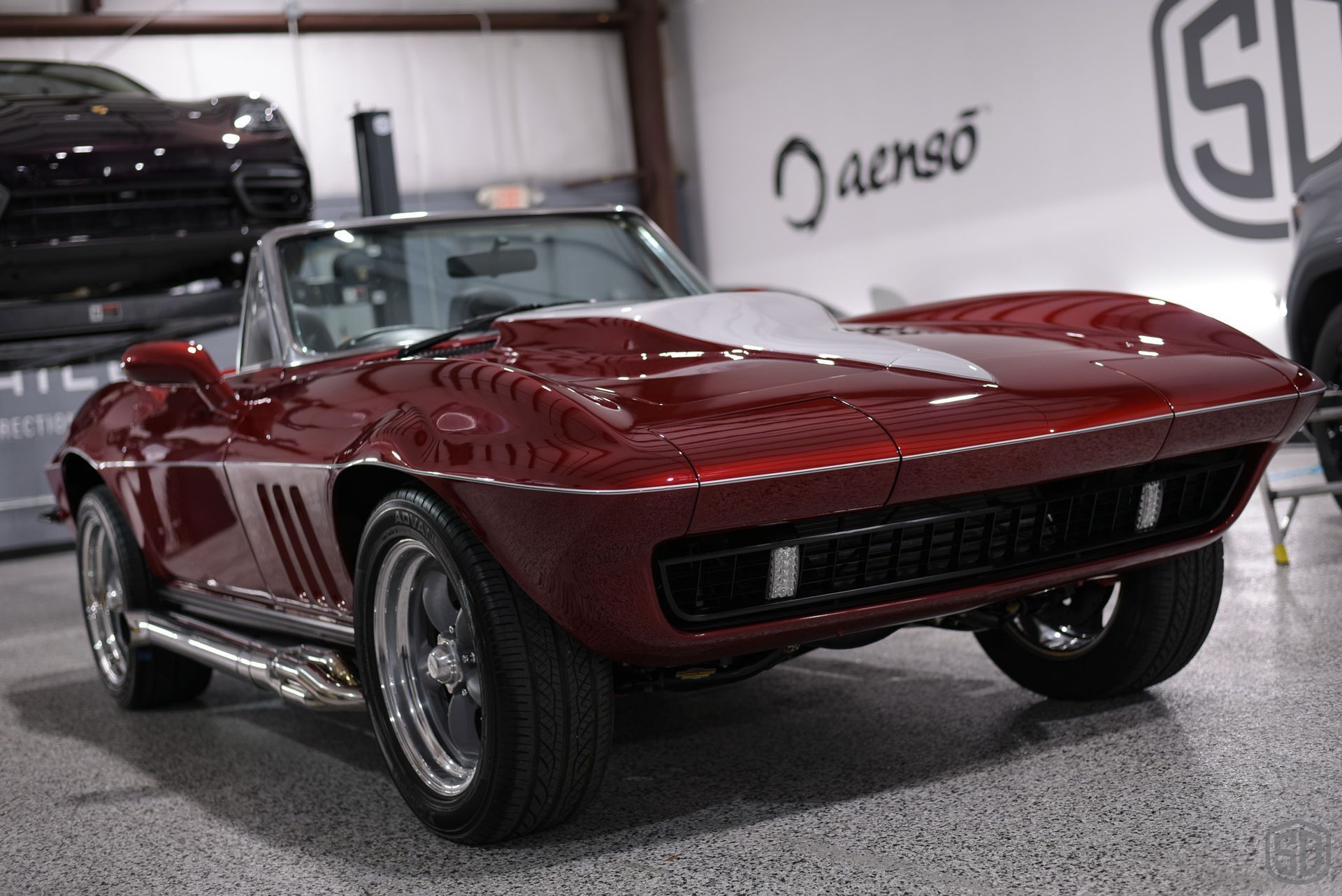 A red corvette convertible is parked in a garage.