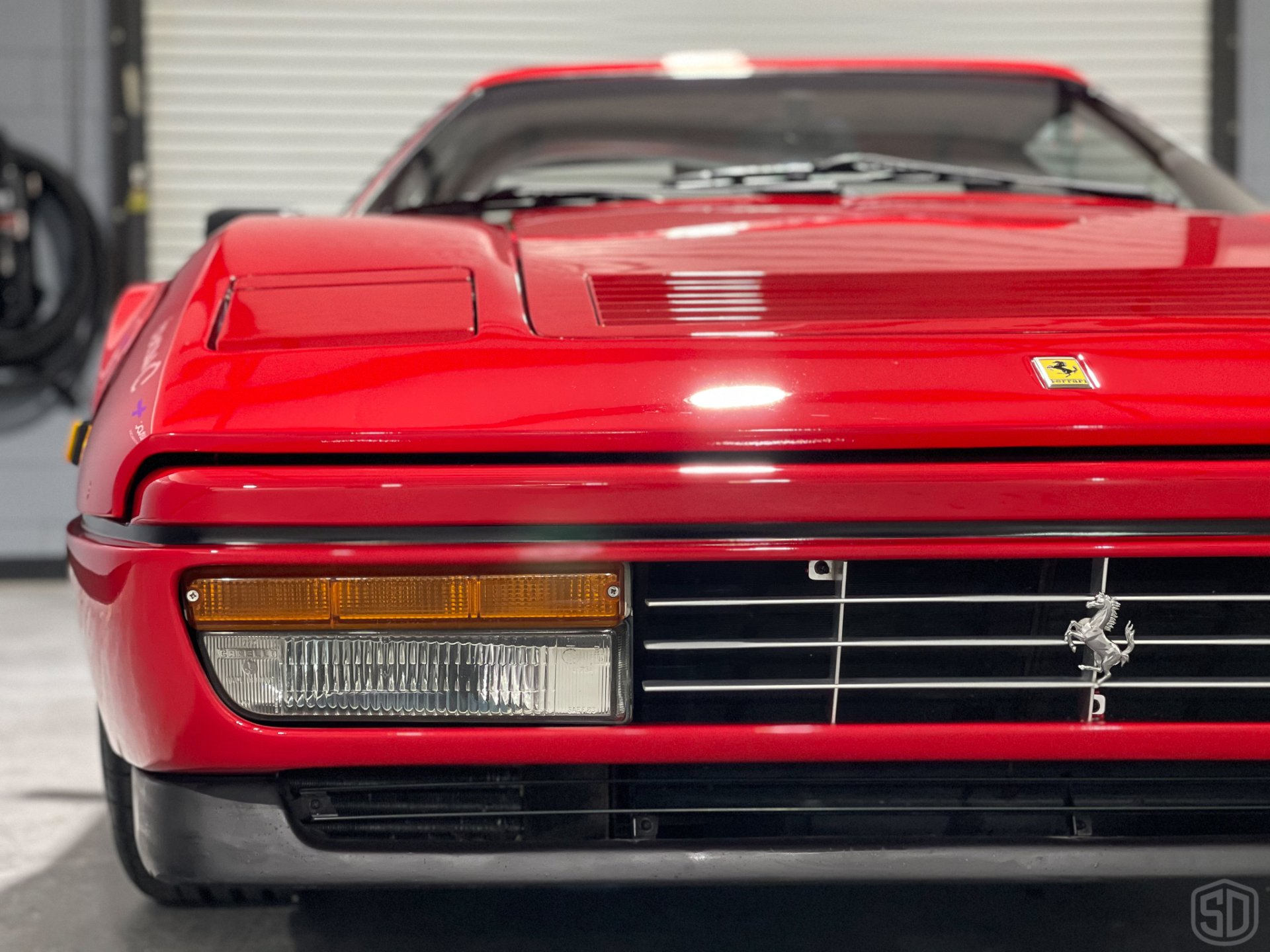 The front end of a red ferrari is parked in a garage.
