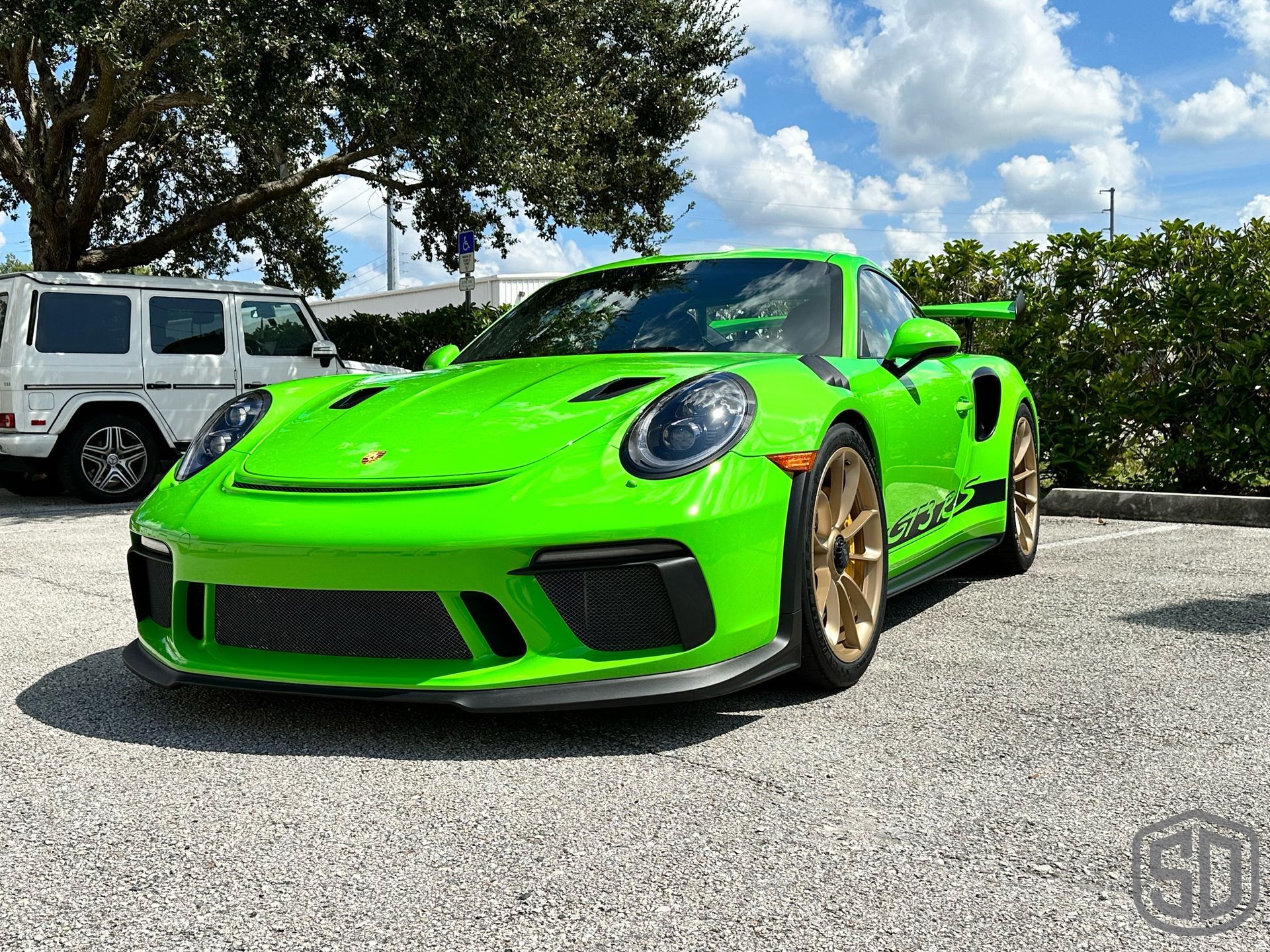 A green porsche 911 gt3 rs is parked in a gravel lot.