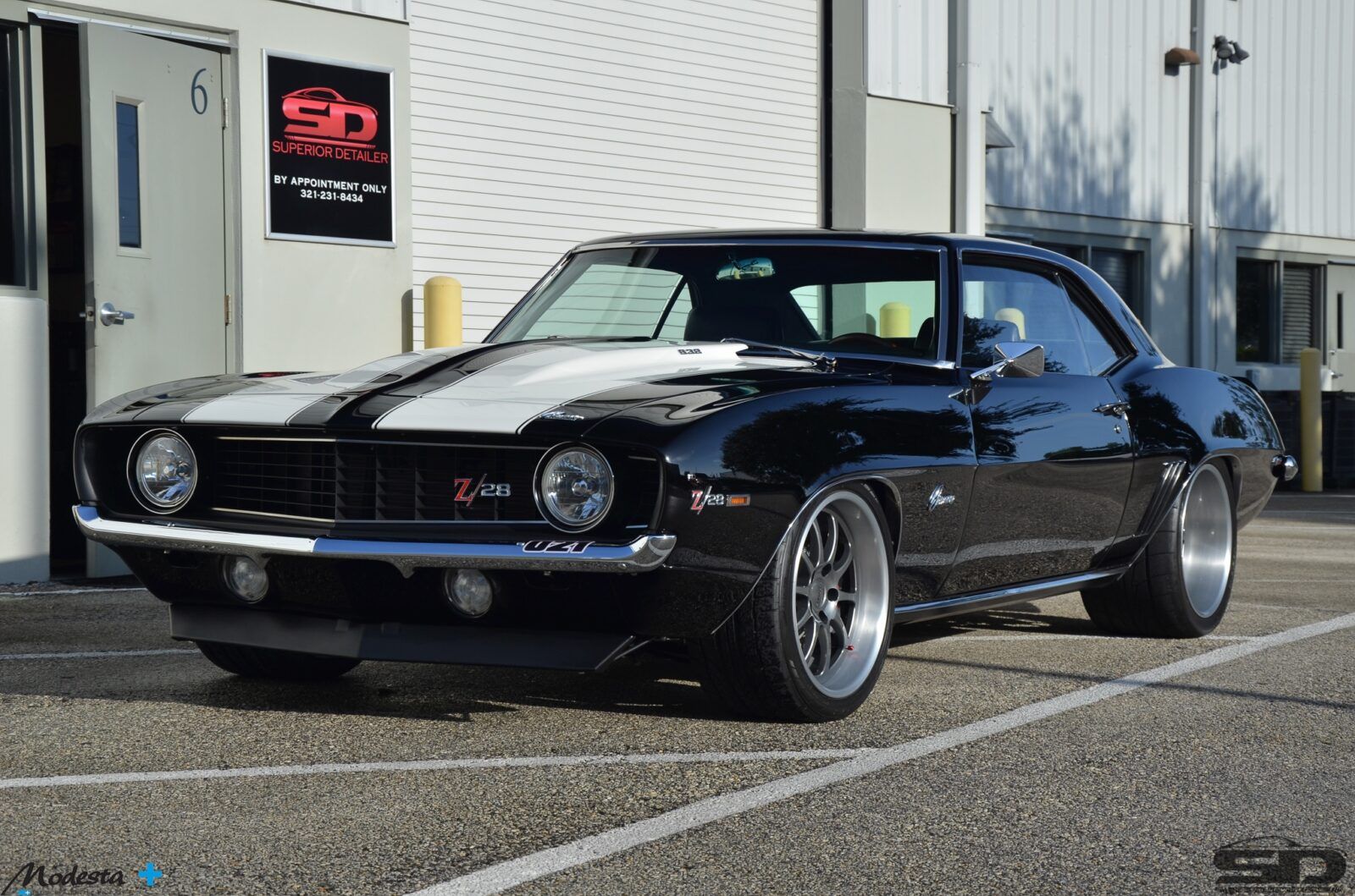 A black and white chevrolet camaro is parked in a parking lot.