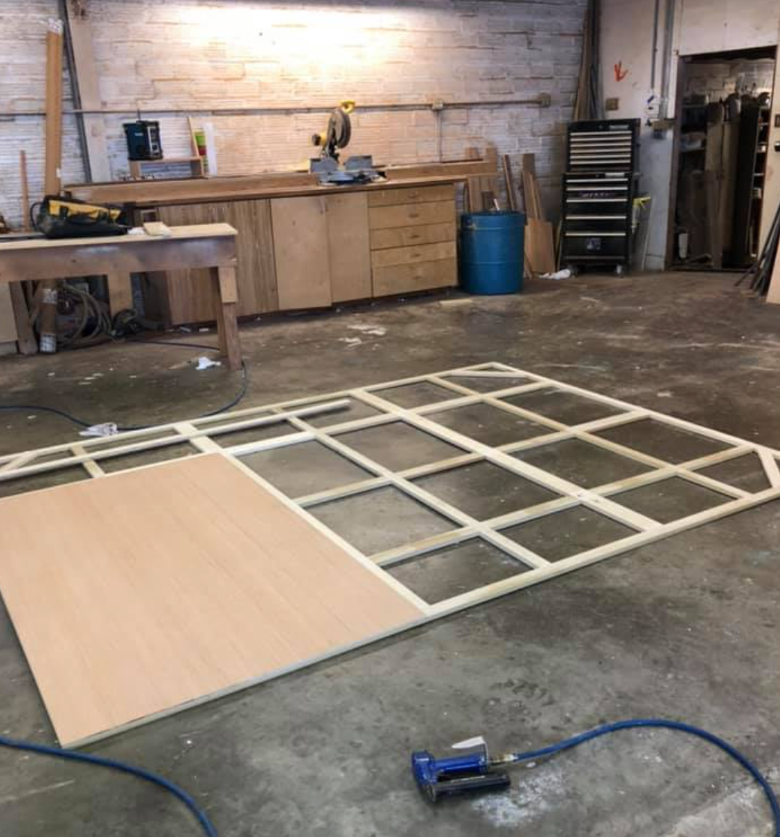 Wooden frame construction in workshop with plywood and tools.