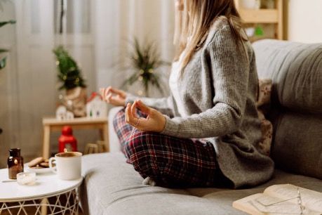 A woman is sitting on a couch meditating.