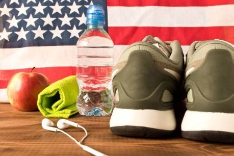 A pair of shoes , a bottle of water , a towel , headphones , an apple and an american flag