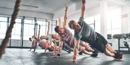 A group of people are doing plank exercises in a gym.