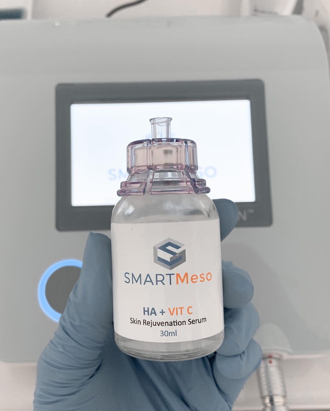 A person is holding a bottle of smart meso in front of a machine.