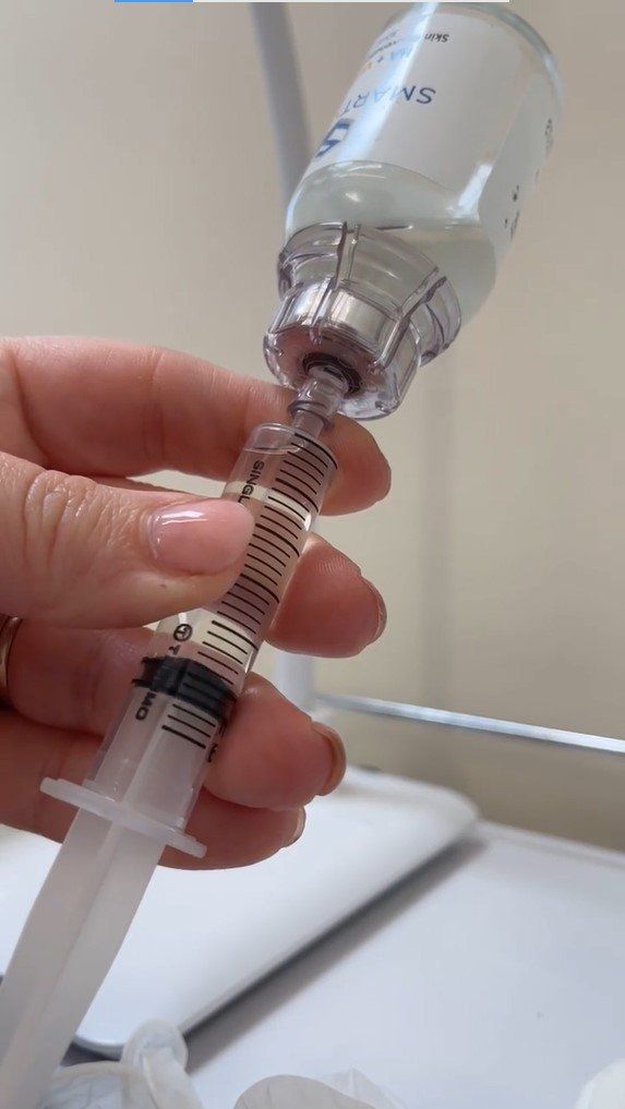 A person is holding a syringe with a bottle of liquid in it.