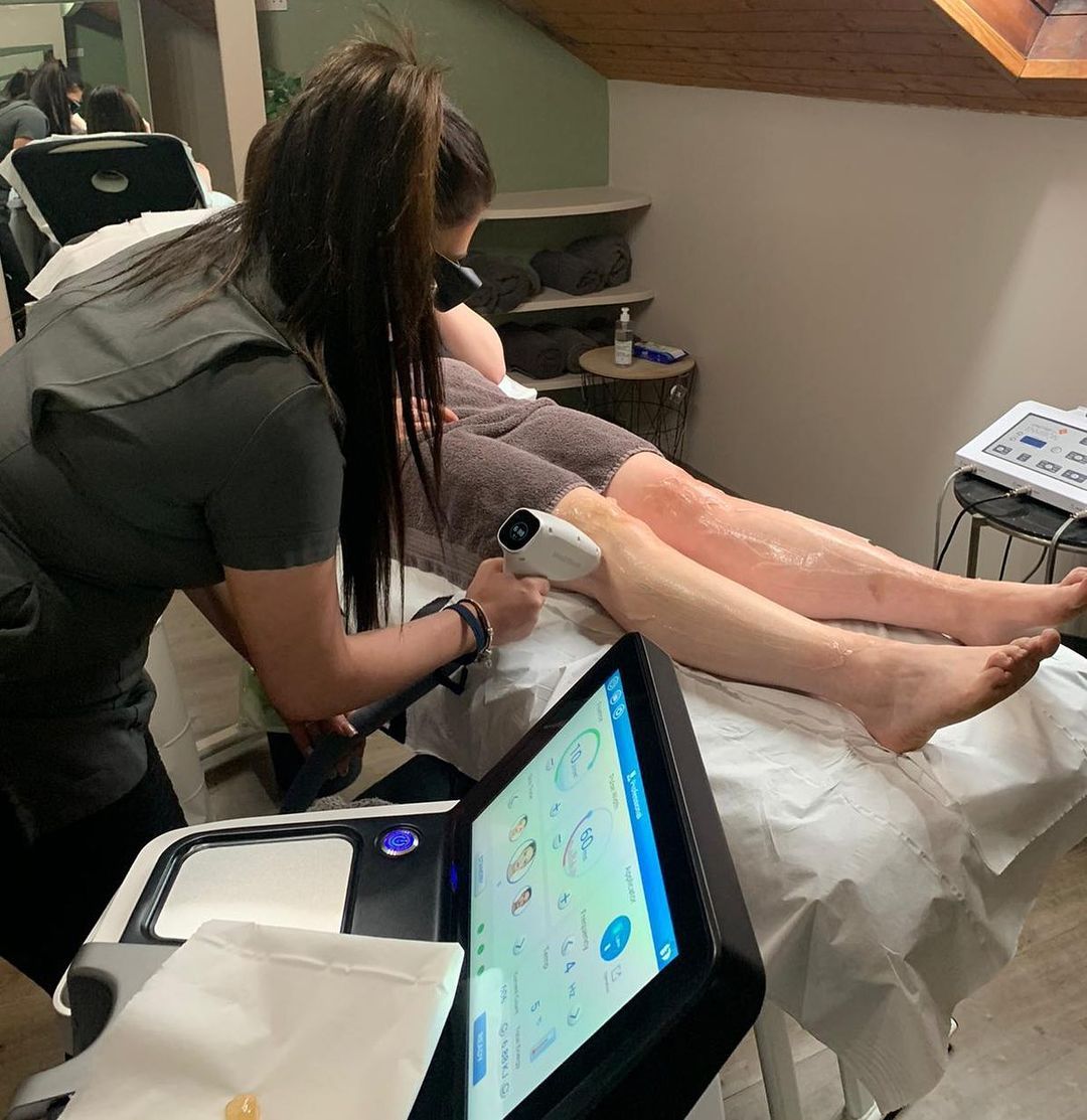 A woman is working on a person 's legs in a room
