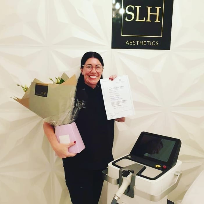 A woman holding a bouquet of flowers in front of a sign that says slh aesthetics
