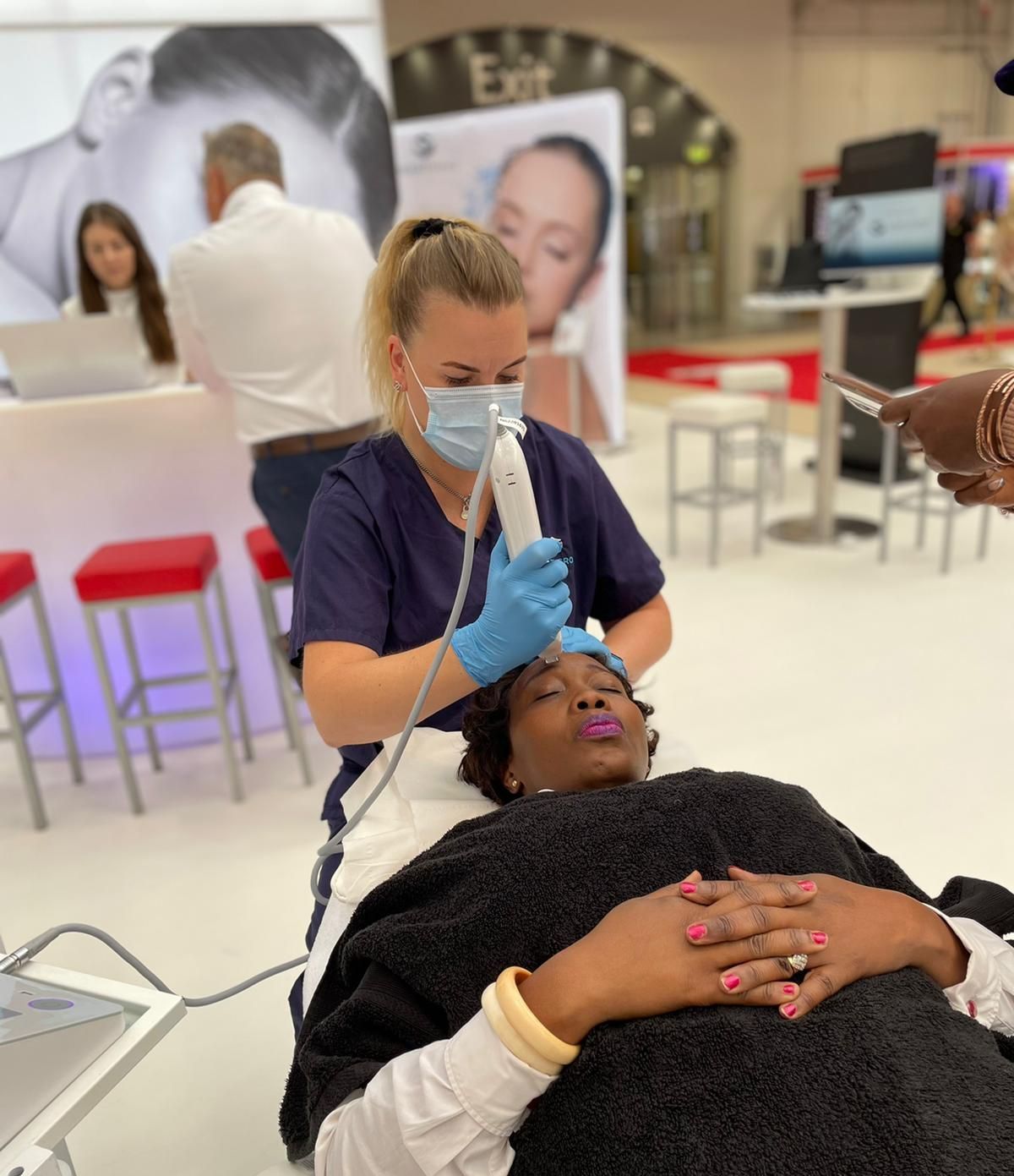 A woman wearing a mask is getting a facial treatment from a nurse.