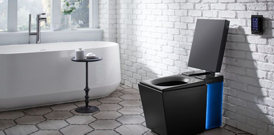 A modern black toilet with a blue panel, open lid, sits in a bathroom next to a bathtub.