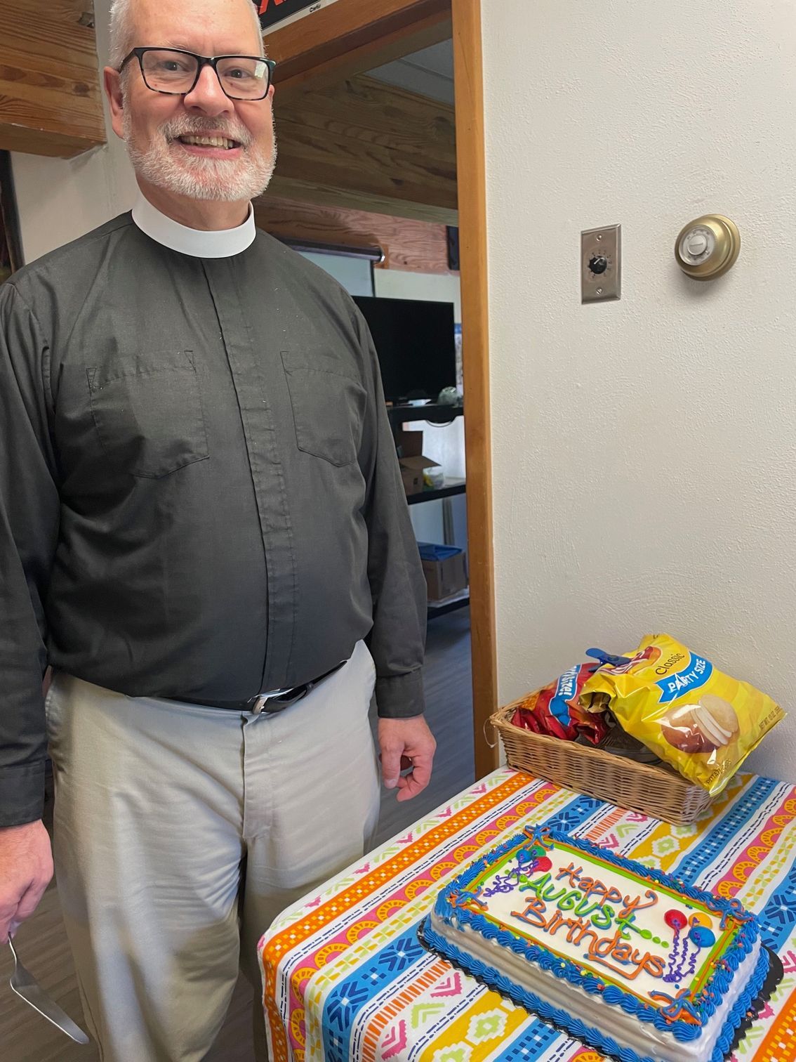 A man is standing next to a birthday cake on a table.