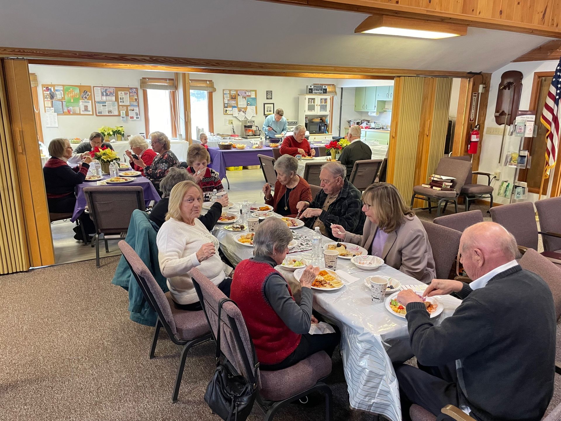 A group of people are sitting at long tables eating food.