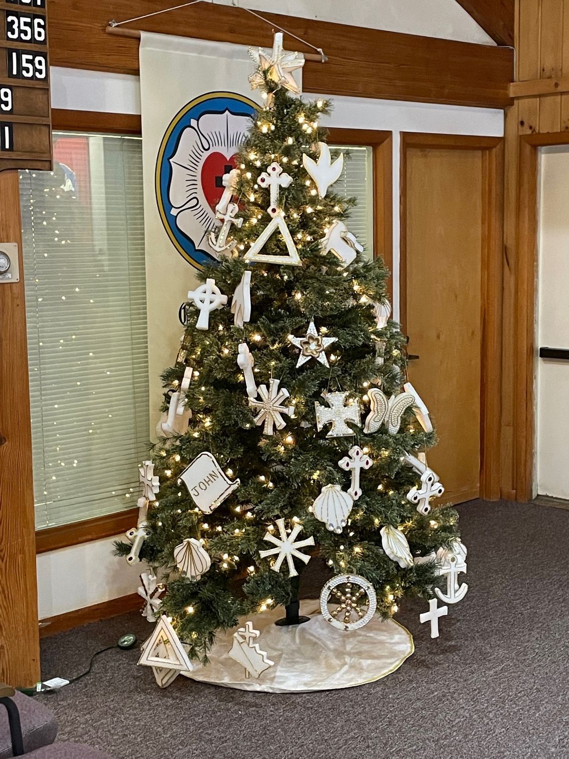 A christmas tree is decorated with white ornaments and lights in a room.