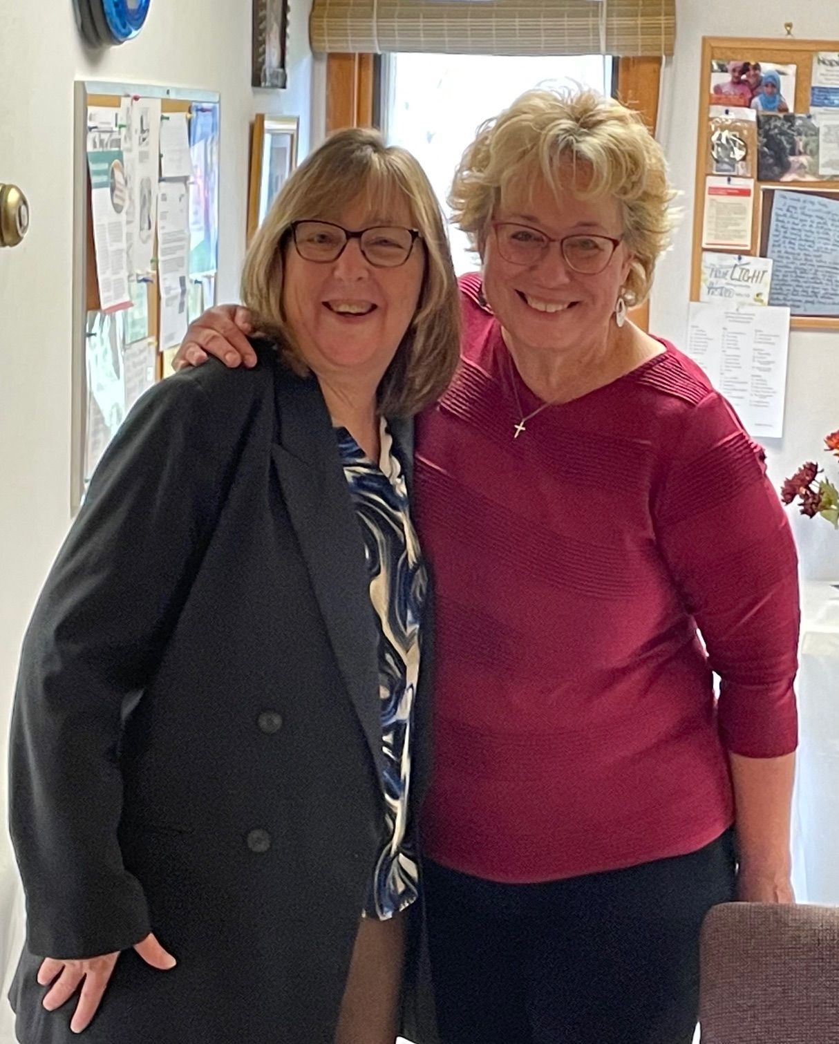 Two women are posing for a picture and one is wearing glasses