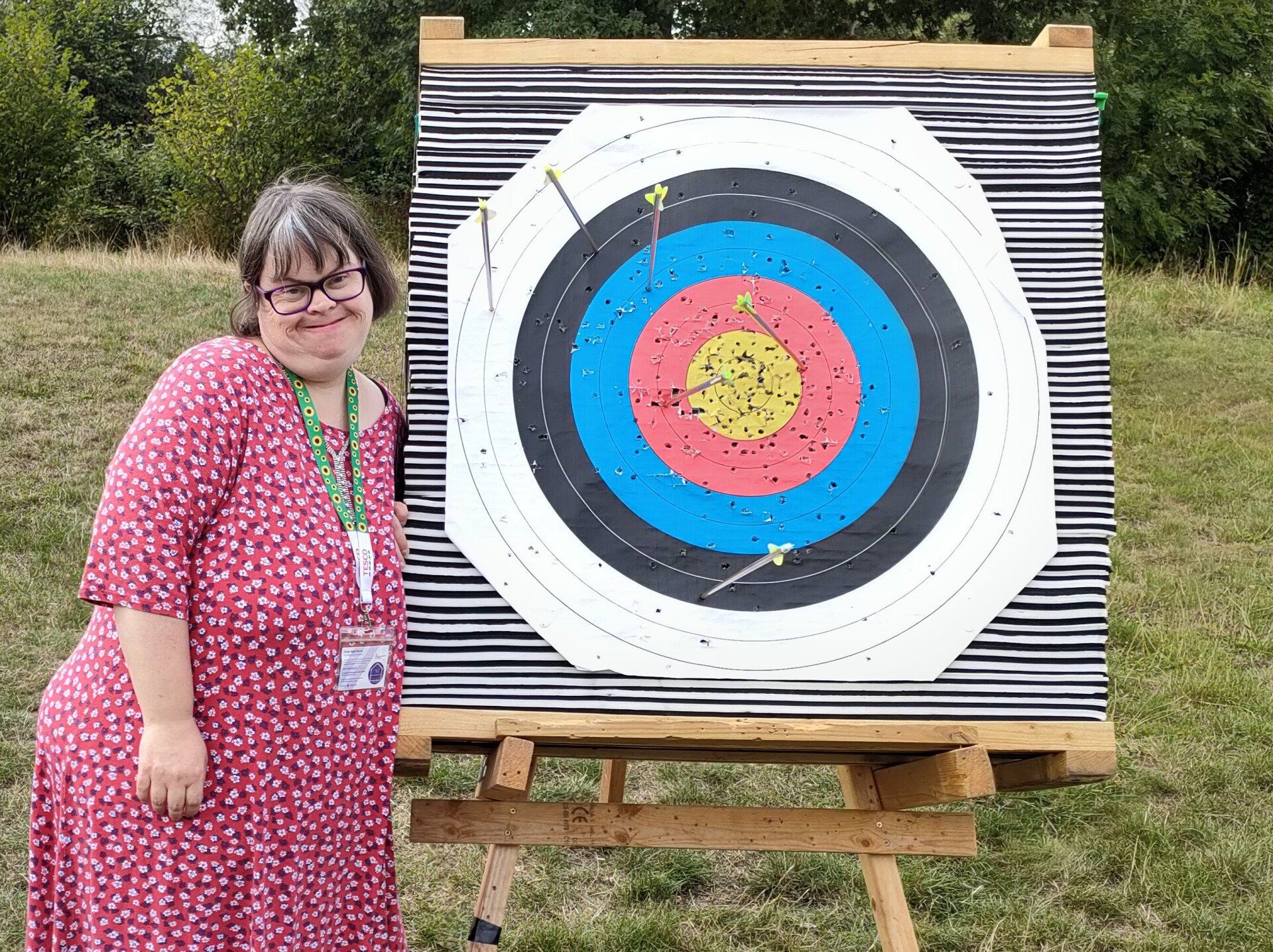 Smiling female FNC member stood beside archery target with seven arrows embedded including two bullseyes