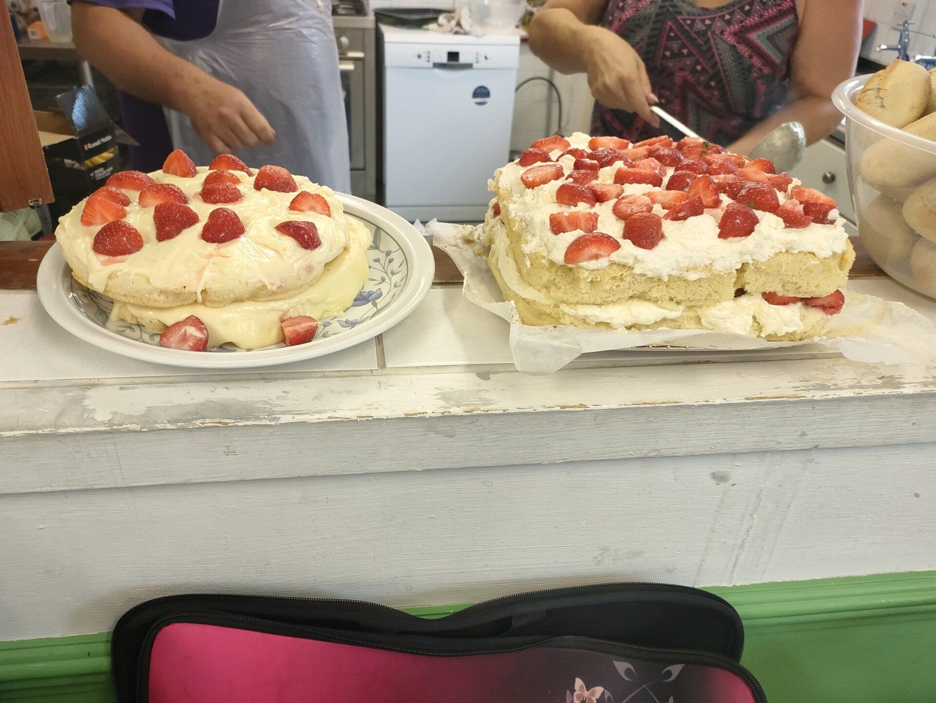 Photo of two large strawberry and cream cakes at serving hatch to kitchen, one round and one square