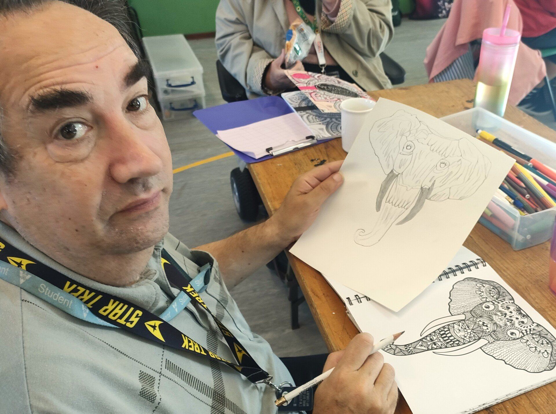 Male FNC Member proudly displays his drawing of an elephants head copied  from Mandala patterned elephant head colouring template