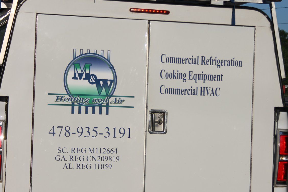 Rear doors of a white service van with business logo and contact info for refrigeration, cooking, and HVAC services.