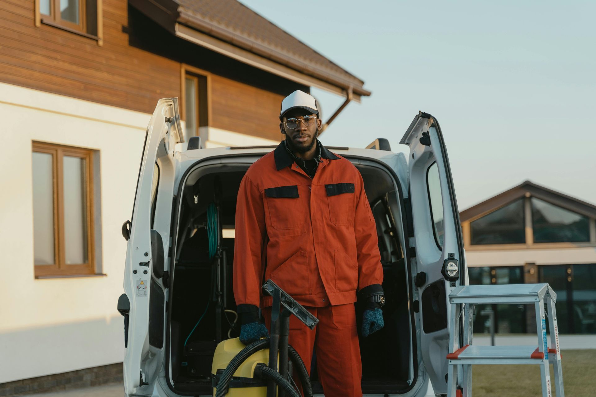 Man in an jumpsuit carrying a vacuum out of a white van
