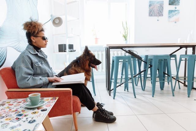 blind woman reading braille with a service dog next to her