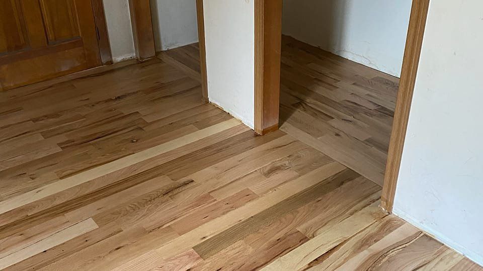 Wood floor installation at doorway; new planks meet existing flooring.