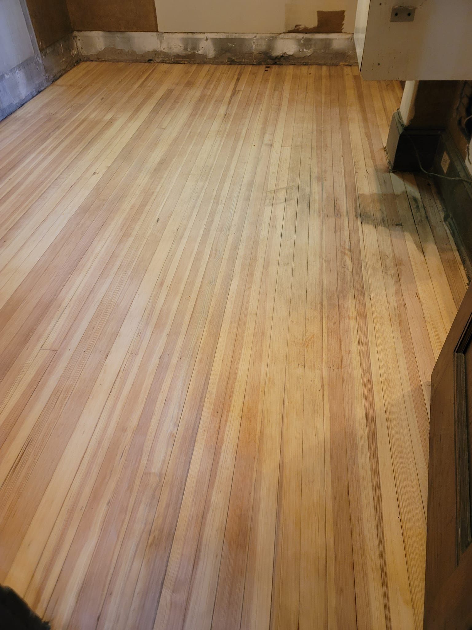 Newly installed hardwood floor in a room, light brown with vertical planks.
