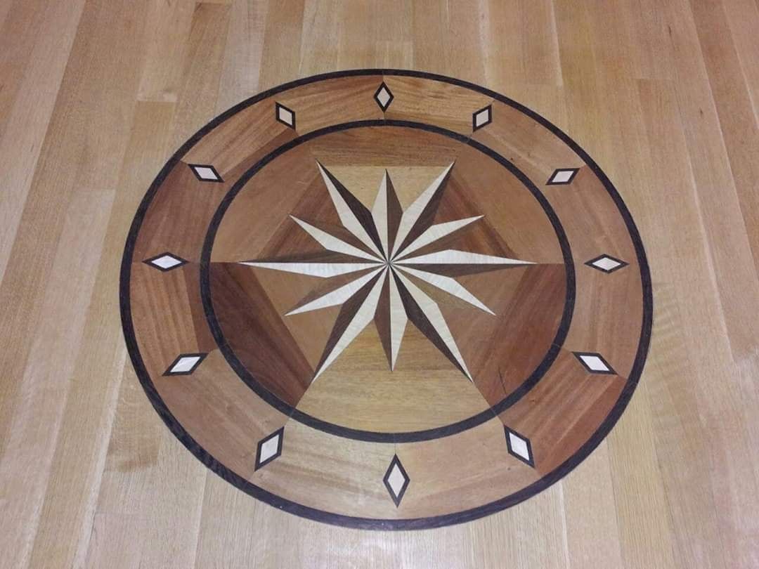 Wooden floor inlay with a compass rose design in various wood tones and diamond accents.