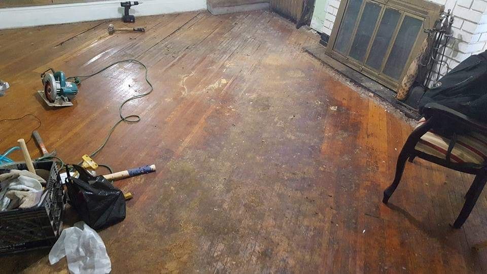 Wooden floor being refinished with tools strewn about and fireplace in the background.