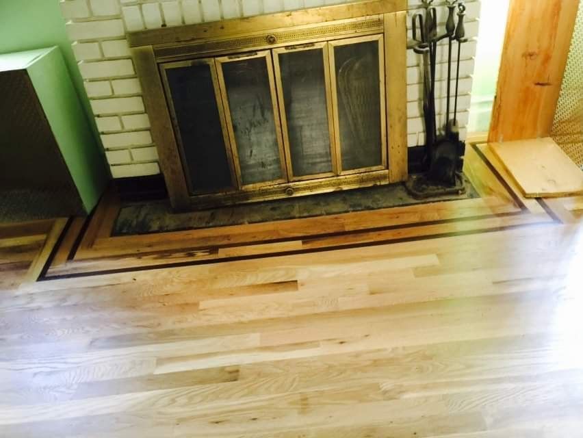 Fireplace with brass doors and hearth, surrounded by light hardwood flooring.