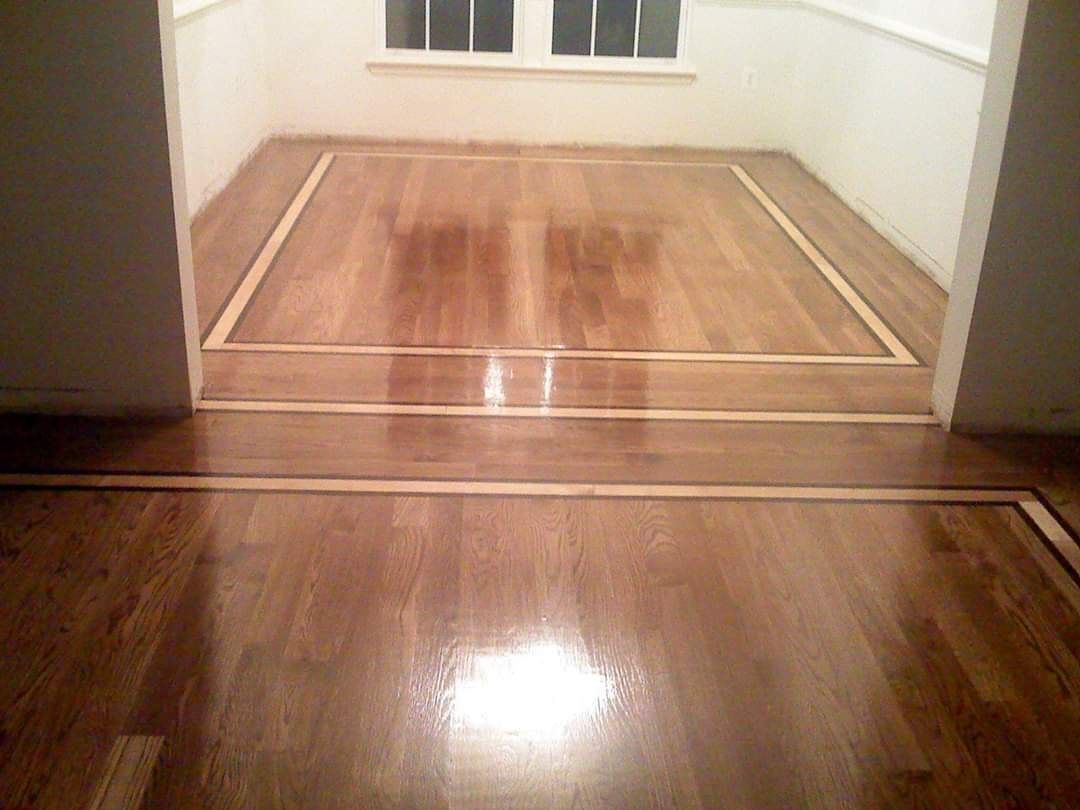 Hardwood floors with inlaid borders, transitioning between rooms, reflecting light.