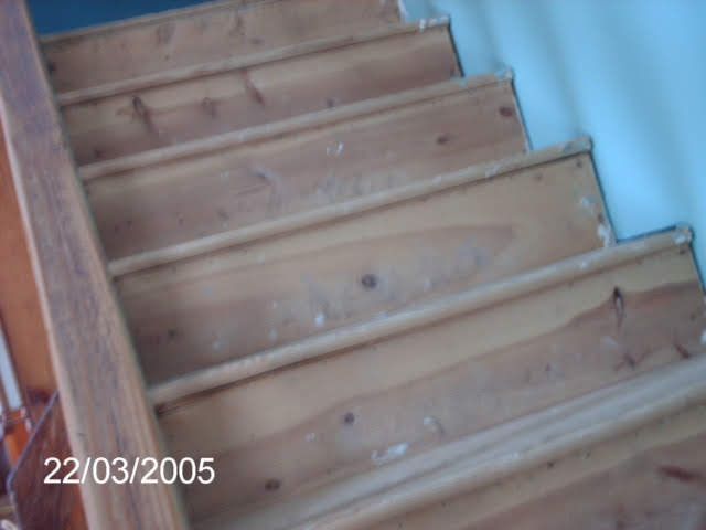Wooden staircase with handrail, ascending. Steps are worn, showing use.