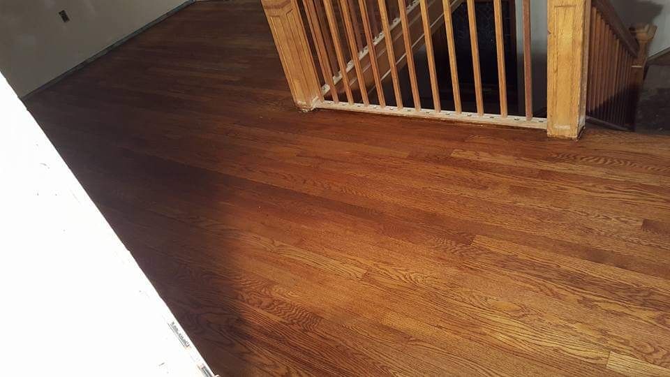 Wooden floor with a staircase in the background. Brown planks of wood, natural light from an unseen source.