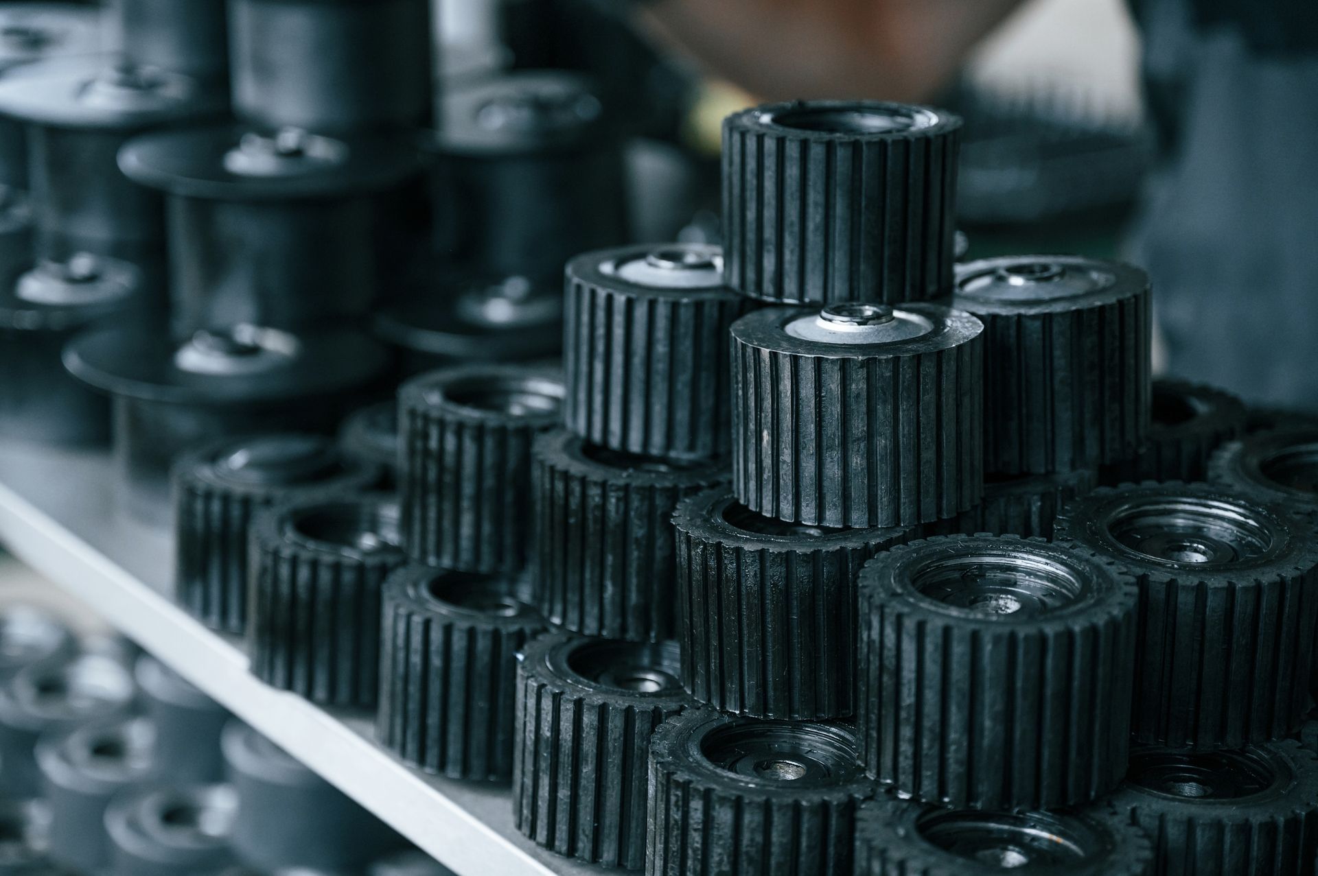 Rows of black gear-like metal cylinders on a production line, viewed in close-up.