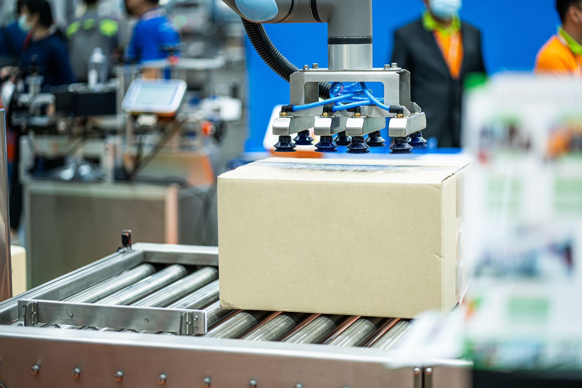Robotic arm placing a cardboard box on a conveyor belt in a factory setting