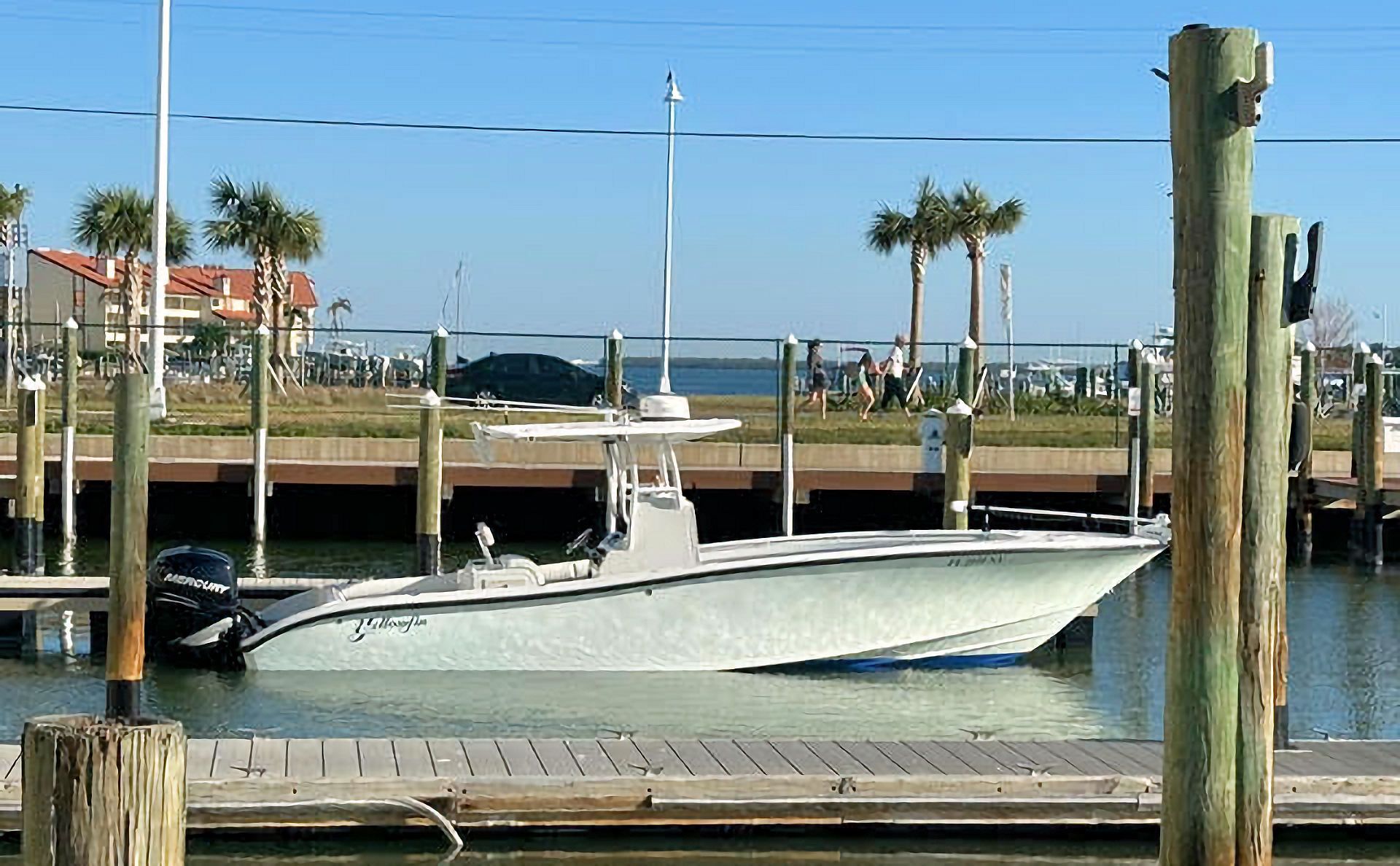 A boat is docked at a dock with a few palm trees in the background