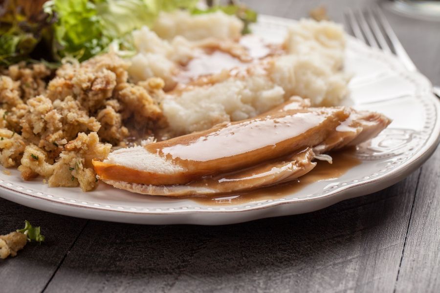 A white plate topped with turkey , mashed potatoes , gravy and stuffing.