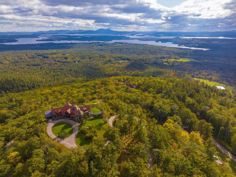 An aerial view of a house on top of a hill surrounded by trees.