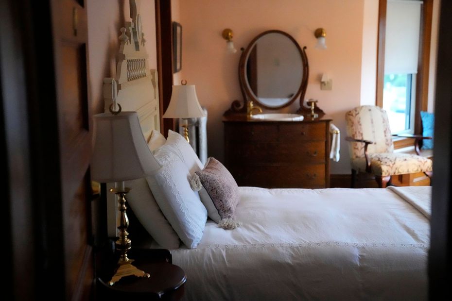 A bedroom with a queen size bed and a mirror and a chair.