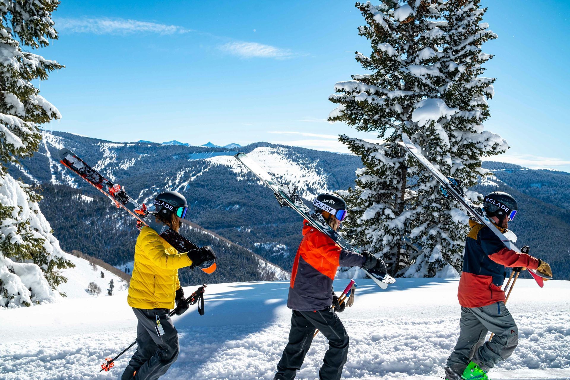 Three people are skiing down a snow covered slope.