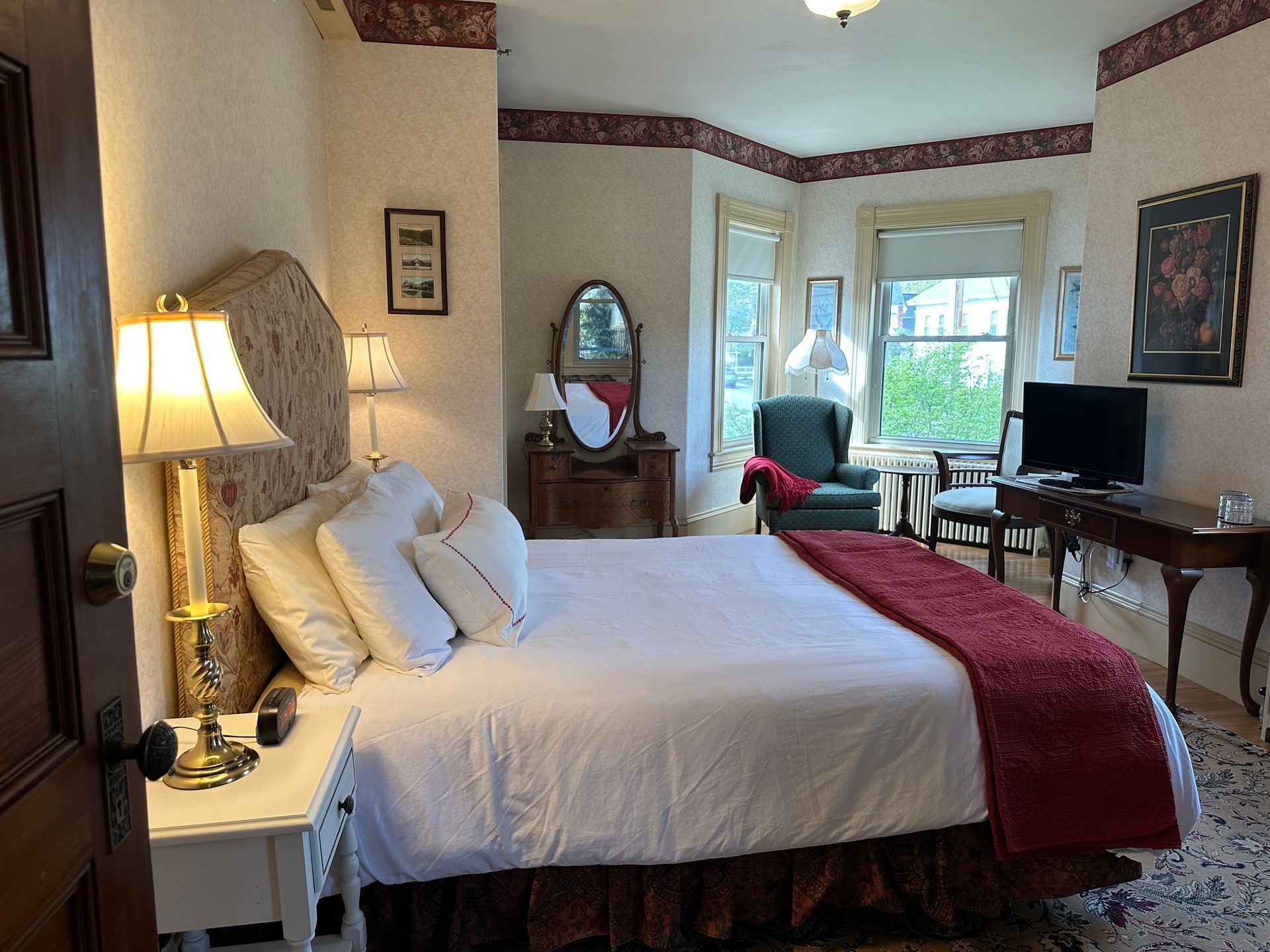 A bedroom with a king size bed , lamps , chairs and a television.