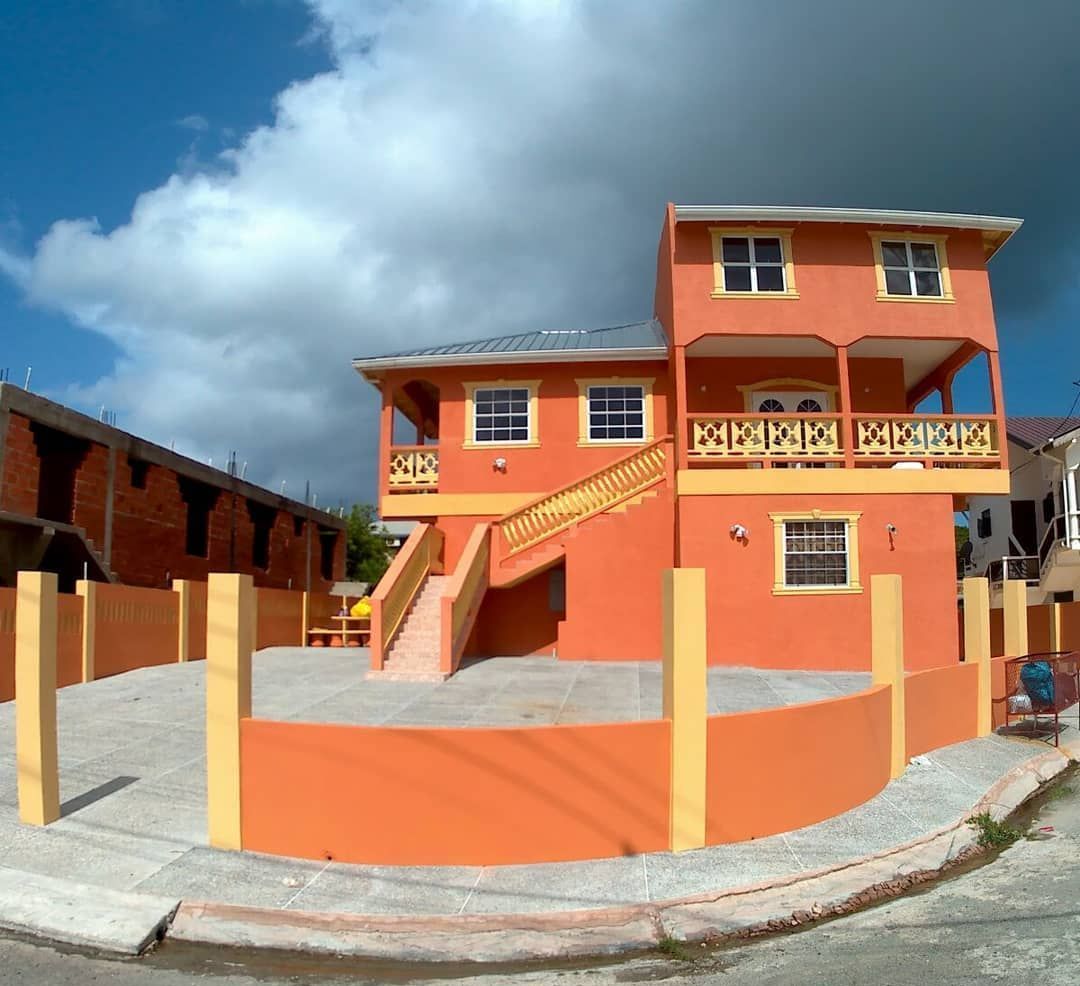 A large orange house with a yellow fence around it