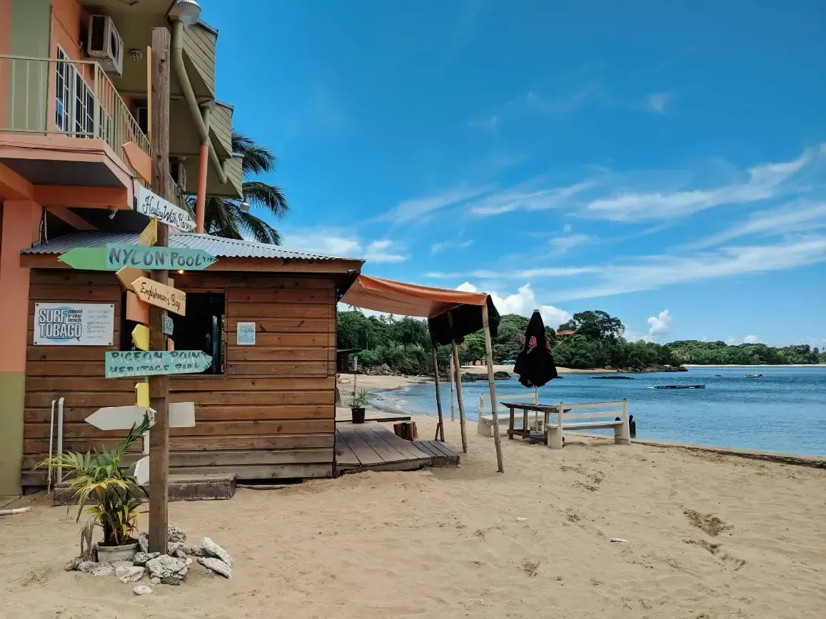 a beach in Tobago with a building in the background and a sign pointing to the right