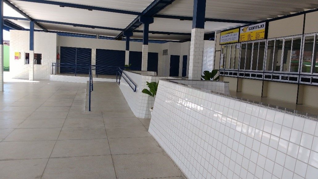 Homem na sala de controle falando ao telefone, supervisionando ônibus estacionados ao ar livre sob abrigo.